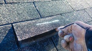Homeowner reviews a roofing contract and storm damage photos at a kitchen table.